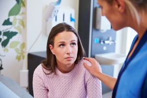 Female Patient Being Reassured By Nurse In Hospital Room