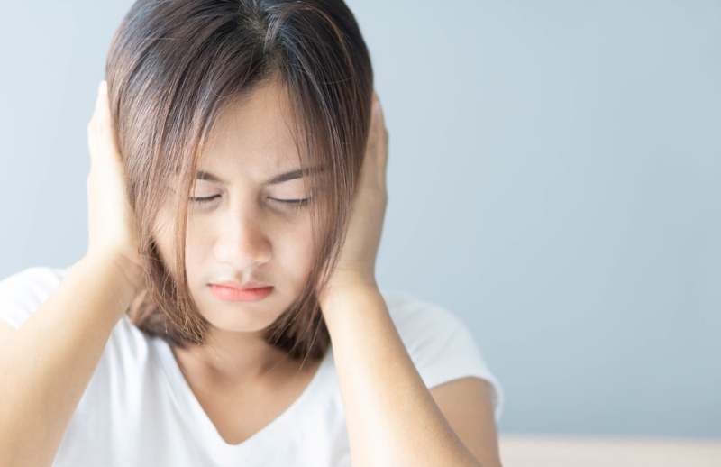 girl holding hands over ears has central sensitization syndrome