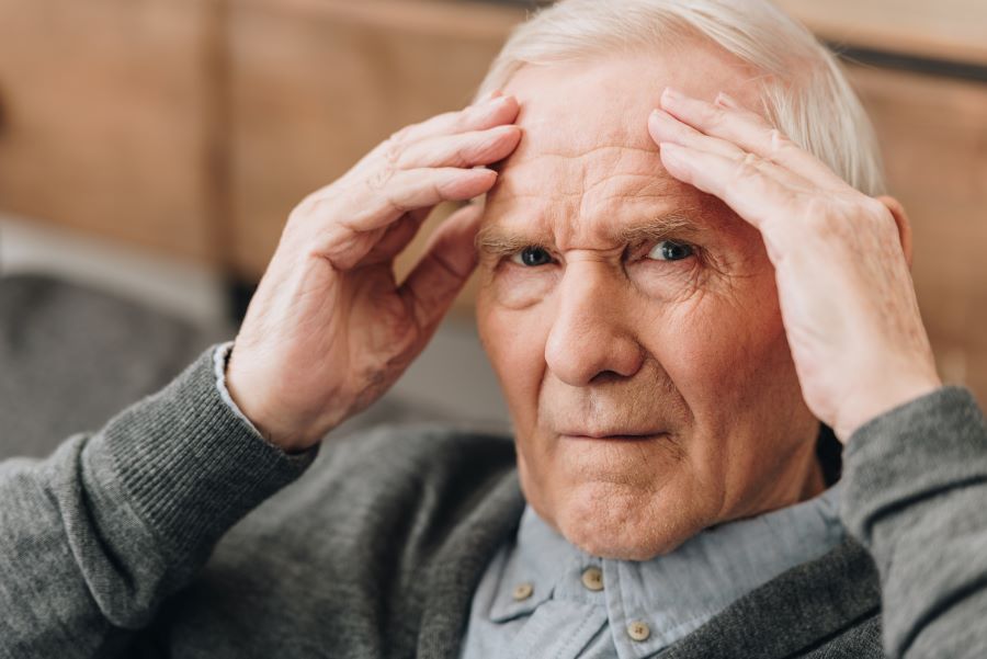 Man with powassan virus encephalitis holding his head.