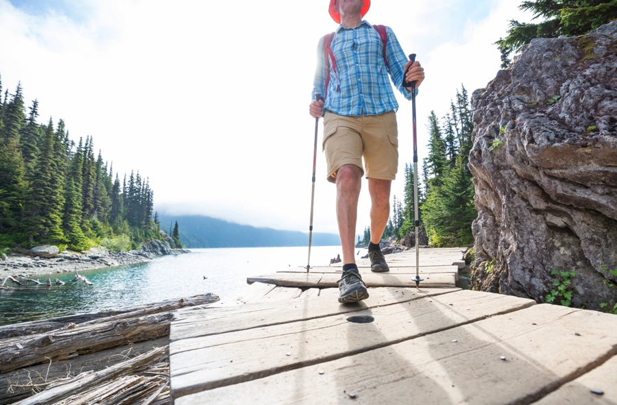 man hiking in shorts along lake