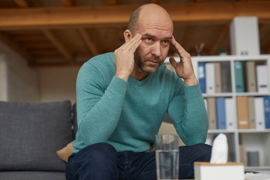 man with fatigue holding head