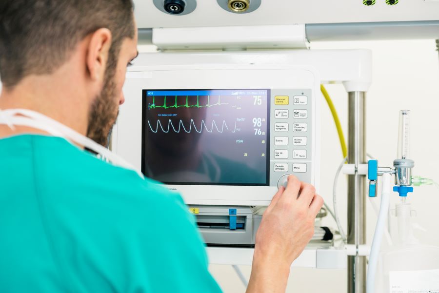 Doctor looking at ECG machine to diagnose lyme carditis in patient admitted for a pacemaker.