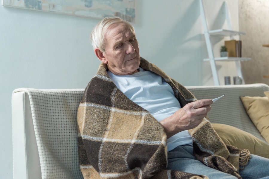 elderly man with Lyme disease and autoimmune disease taking his temperature