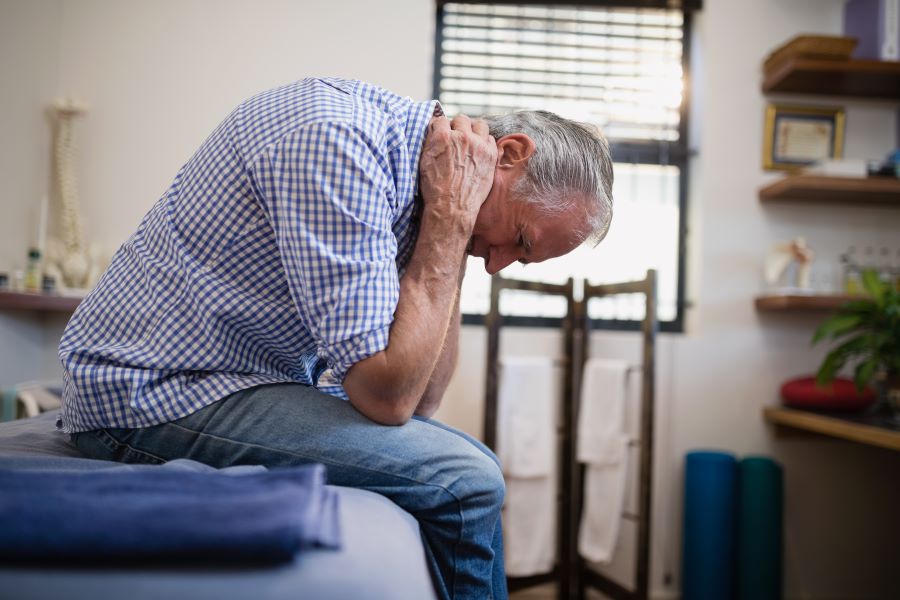 Man with Lyme disease and meningitis holding his neck in pain.