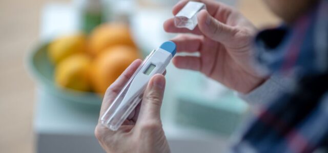 Man with a Borrelia infection checking thermometer reading.