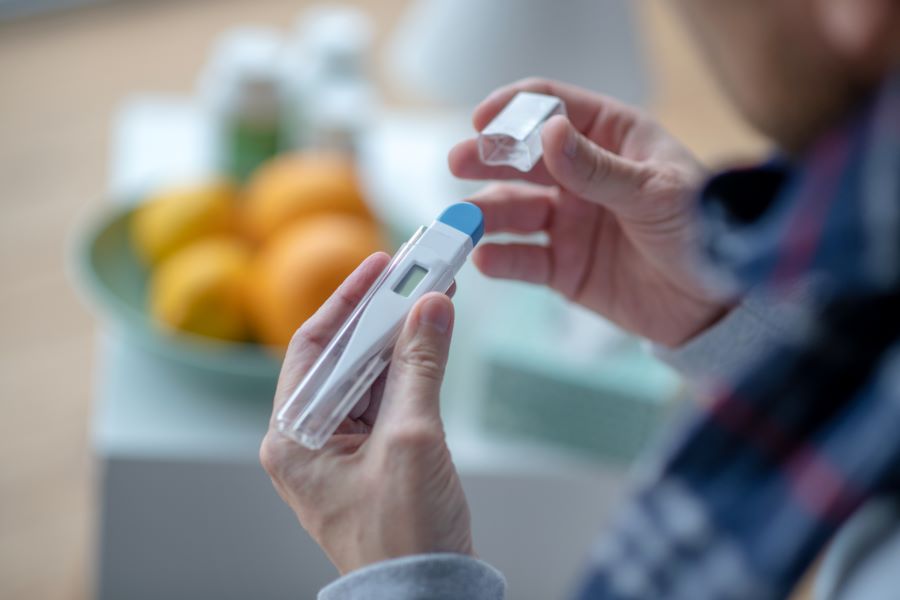 Man with a Borrelia infection checking thermometer reading.