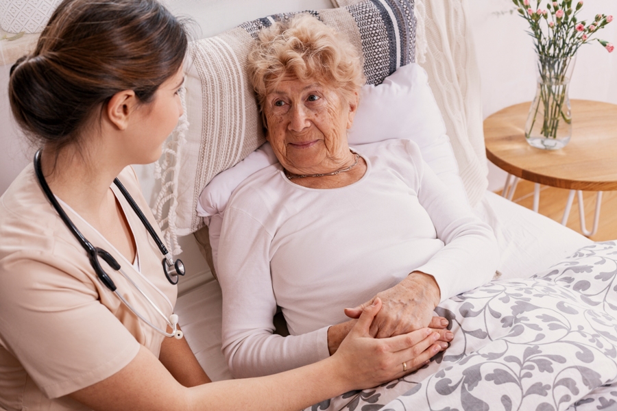 Health aid helping old woman in bed who had a tick bite and Lyme disease.