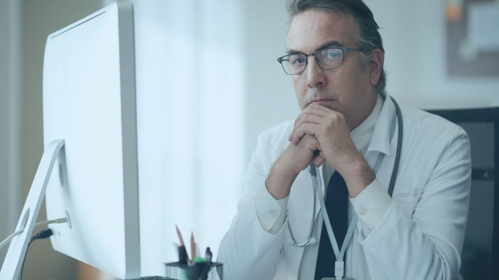 Physician thoughtfully reviewing clinical notes related to complex Lyme disease care