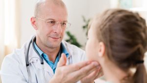 Doctor examining facial symmetry in a child with suspected facial nerve palsy.