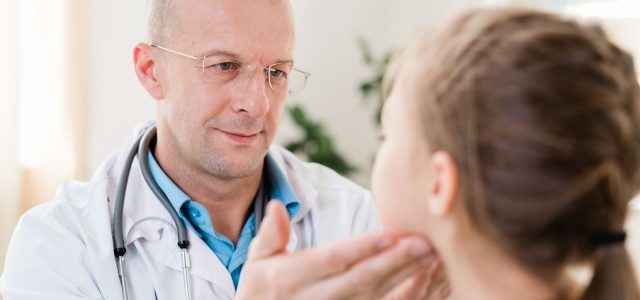 Doctor examining facial symmetry in a child with suspected facial nerve palsy.