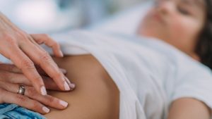 doctor examining child with abdominal pain and possible Lyme disease symptoms