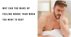 Tired man sitting up in bed after waking in the morning