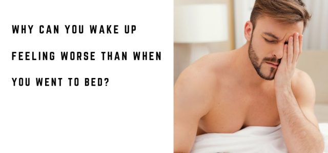 Tired man sitting up in bed after waking in the morning